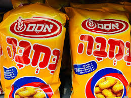Two bags of yellow snack packaging with red and white branding display Hebrew text and an image of crunchy Bamba snacks on the front.